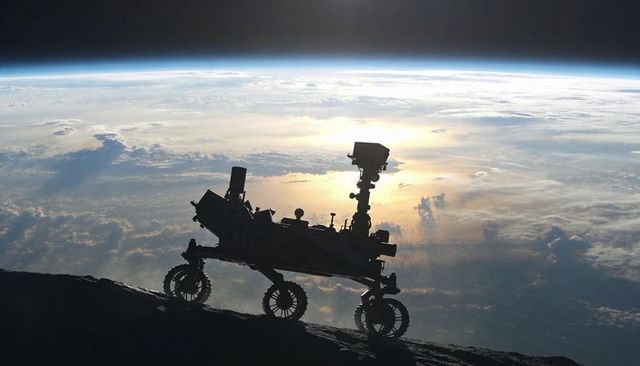 Silhouetted six-wheel rover climbing rocky ridge against sunlit earth horizon futuristic