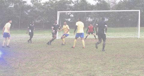 Amateur soccer defenders contesting airborne ball in penalty area, goalkeeper poised