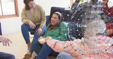 Laughing friends sharing popcorn while sitting on floor with digital globe overlay