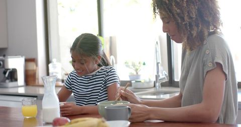Joyful Mother and Daughter Sharing Breakfast in Sunlit Kitchen