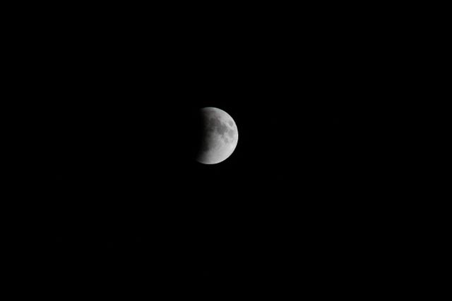 Captivating view of a lunar eclipse with half of the moon shaded, set against a dark night sky. Ideal for use in educational content about astronomy, science presentations, celestial event documentation, and enhancing visual storytelling in space-themed projects.