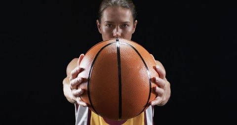 determined female basketball player holding ball against black background - Download Free Stock Images Pikwizard.com