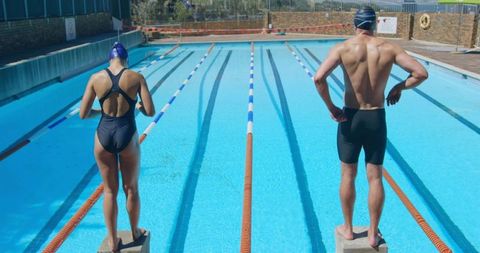 Competitive swimmers preparing for dive at outdoor pool