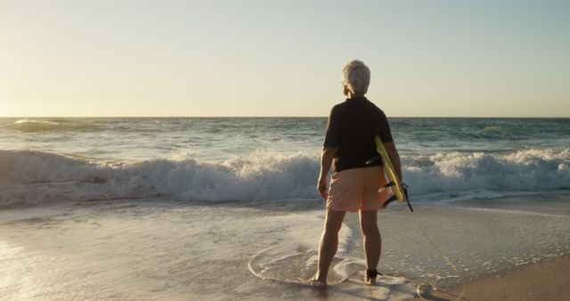 Senior man with surfboard standing on beach watching waves - Download Free Stock Images Pikwizard.com