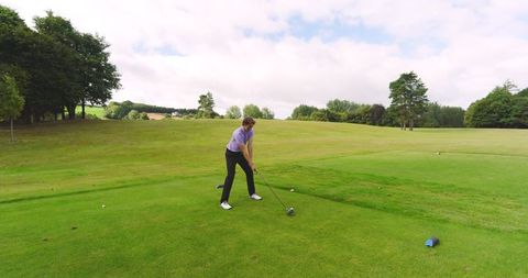 Focused Golfer Swinging Driver Back on Green Course
