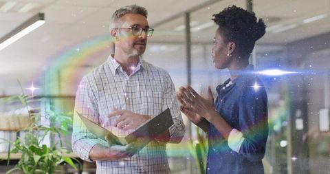 Colleagues discussing project in modern open-plan glass office with creative lens flare