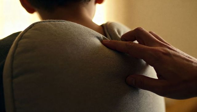 Caregiver hand resting on child padded backpack cushion conveying tenderness and warmth