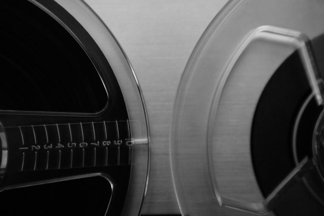 Close-up image of a vintage reel-to-reel tape recorder in black and white highlights details of the audio equipment, evoking a sense of nostalgia. Perfect for use in articles about vintage audio technology, retro themes, or classic music recording history.