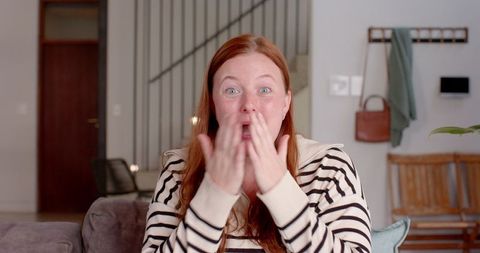 Surprised Woman in Striped Sweater Sitting on Comfortable Sofa at Home