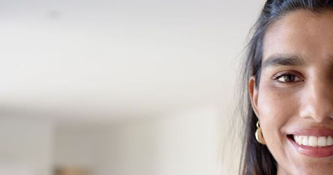 Smiling woman showing hoop earrings in bright space
