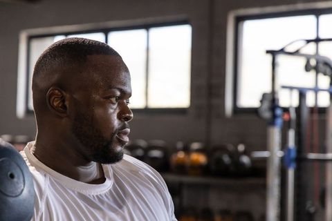 Focused african american athlete catching breath after intense workout in industrial gym