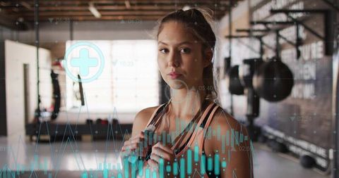 Standing female athlete holding jump rope in gym with biometric fitness analytics