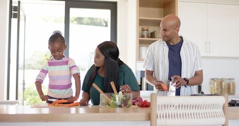 African american family preparing healthy meal together in bright modern kitchen island