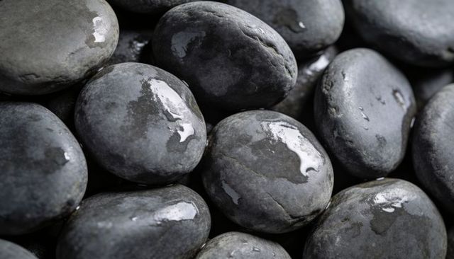 Glossy wet river stones reflecting soft light with water droplets close-up texture