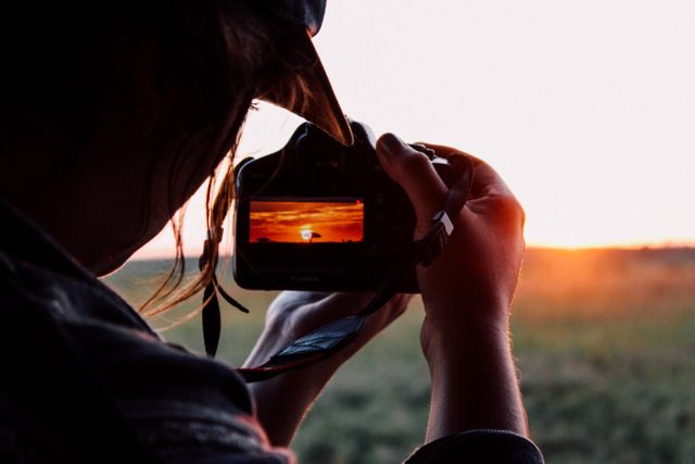 Photographer capturing a beautiful sunset in the field. Ideal for content focused on photography, nature, hobbies, creativity, and outdoor activities. Can be used for blogs, educational materials, advertisements, and inspirational quotes.