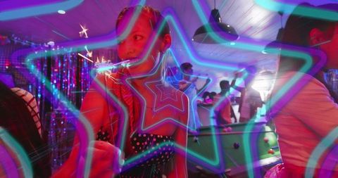 Woman holding sparkler in neon pool hall celebrating under star-shaped light trails