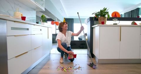 Senior friends enjoying clean-up after fun birthday celebration in kitchen