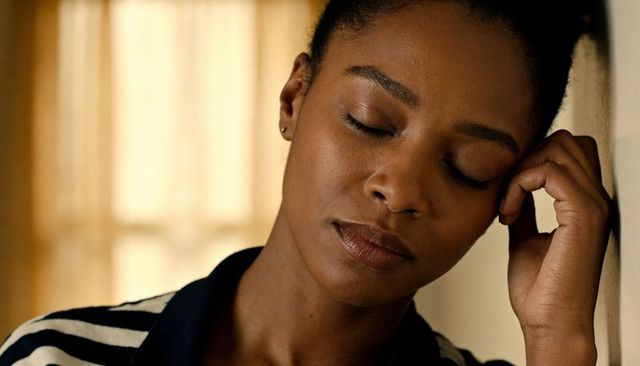 Leaning woman resting head on hand by window reflecting quiet introspection and calm