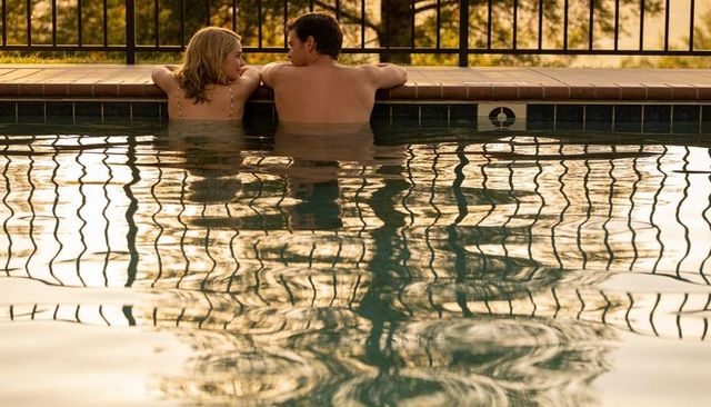Couple leaning on pool edge at golden hour with reflective water patterns