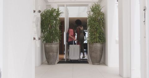 Diverse friends enter hotel with luggage, symbolizing adventure