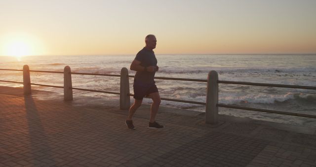 Senior man jogging along ocean promenade at sunrise - Download Free Stock Images Pikwizard.com