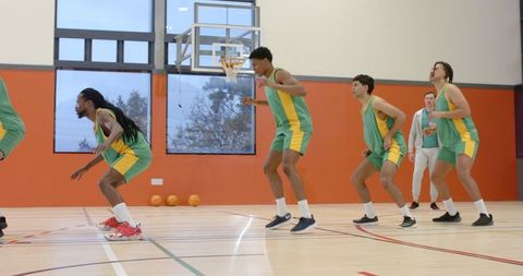 Basketball team practicing defensive drills in indoor court