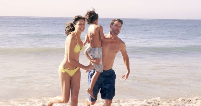 Family running and smiling near ocean waves during summer vacation. Perfect for travel brochures, family-oriented advertisements, and content promoting beach holidays.