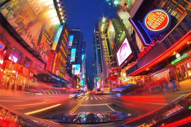 This depiction of Times Square at dusk, showcasing bright neon lights and blurred motion from the bustling traffic, captures the energetic and vibrant atmosphere of New York City's iconic tourist hub. Ideal for projects related to tourism, urban life, cityscapes, cultural references, and advertisements, this image conveys excitement and the lively spirit of the city.