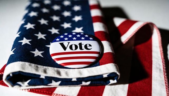 Vote button on folded american flag fabric with stars and stripes