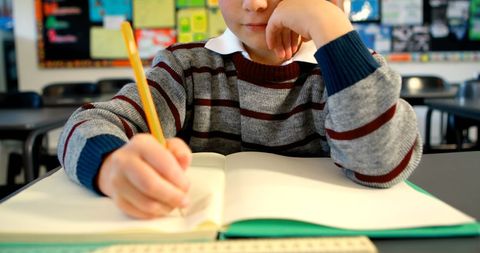 Young Student Writing in Classroom with Focused Expression - Download Free Stock Images Pikwizard.com
