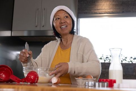 Joyful Senior Asian Woman Preparing Ingredients in Rustic Kitchen
