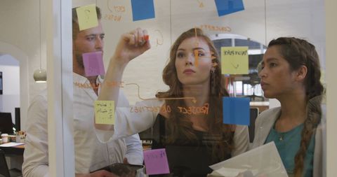 Diverse team brainstorming using sticky notes in modern office