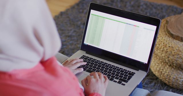 Woman analyzing spreadsheet data on laptop, suitable for illustrating concepts of remote work, data analysis, business planning, and digital technology use in a home office environment. Ideal for blogs, websites, and articles about working from home, productivity, and professional development.