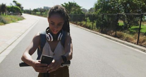 Young Woman on Electric Scooter Checking Smartphone Outdoors