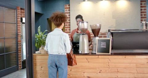 African american customer ordering coffee from smiling barista at rustic cafe counter