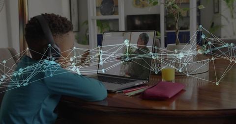 Child attending remote learning at dining table wearing headset with digital network overlay
