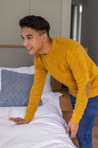 Casual Young Man Leaning on Bed in Contemporary Bedroom