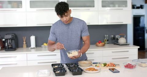 Young african american man prepping healthy meals at modern minimalist kitchen island