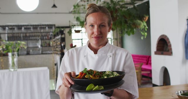 Smiling female chef presenting gourmet dish in modern kitchen - Download Free Stock Images Pikwizard.com