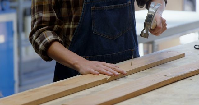 Carpenter Wearing Denim Apron Hammering Nail in Workshop - Download Free Stock Images Pikwizard.com