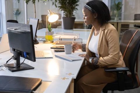 African american professional working at modern open-plan office desk with laptop