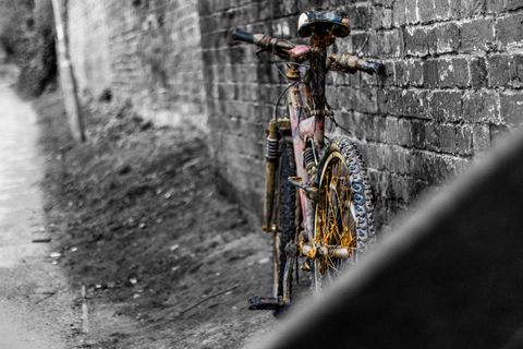 Rusty bicycle against brick wall in alleyway