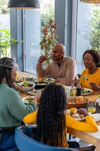 African american family sharing cozy sunlit dinner around wooden dining table