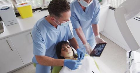 Dentist and assistant reviewing dental x-ray while preparing patient for restorative care