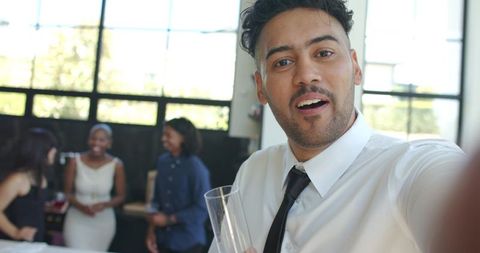 Man in white shirt taking selfie with friends at modern reception gathering