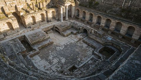 Aerial view revealing roman bath complex ruins with paved courtyard and columns