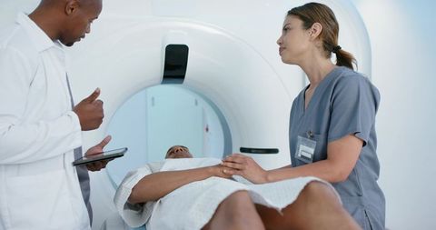 African american team performing ct scan while nurse comforting patient in radiology