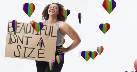 Plus-size woman holding 'beautiful is not a size' sign laughing with rainbow hearts