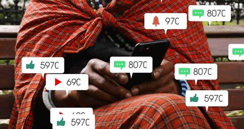Older man holding smartphone on park bench with social media notifications red plaid wrap