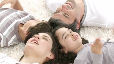 Joyful Family Lying on Carpet Laughing Together